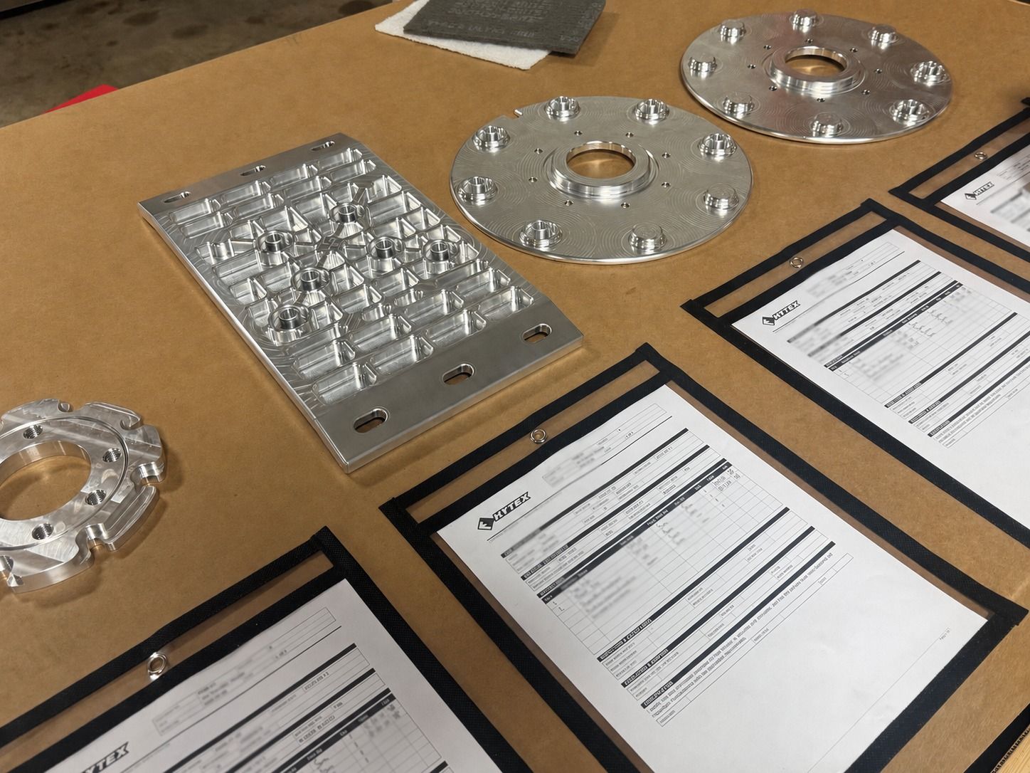 Machined aluminum parts laid out with their job paperwork